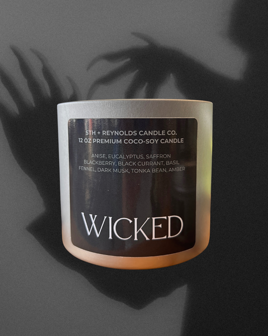 Candle labeled 'Wicked' by 5th + Reynolds Candle Co. on a dark background, showing shadows of a figure with creepy hands with claws.